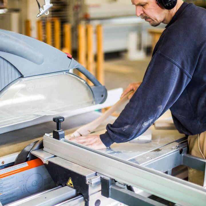 Mitarbeiter in Produktionshalle an Maschine