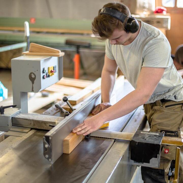Mitarbeiter, der Holz für ein Möbelstück zuschneidet