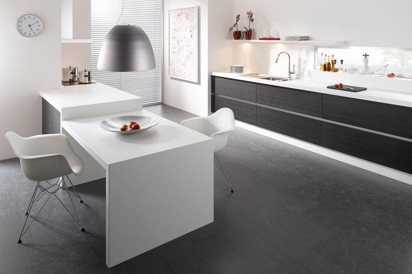 Impression einer einzeiligen Küchengestaltung in schwarz-weiß mit Esstisch für Zwei