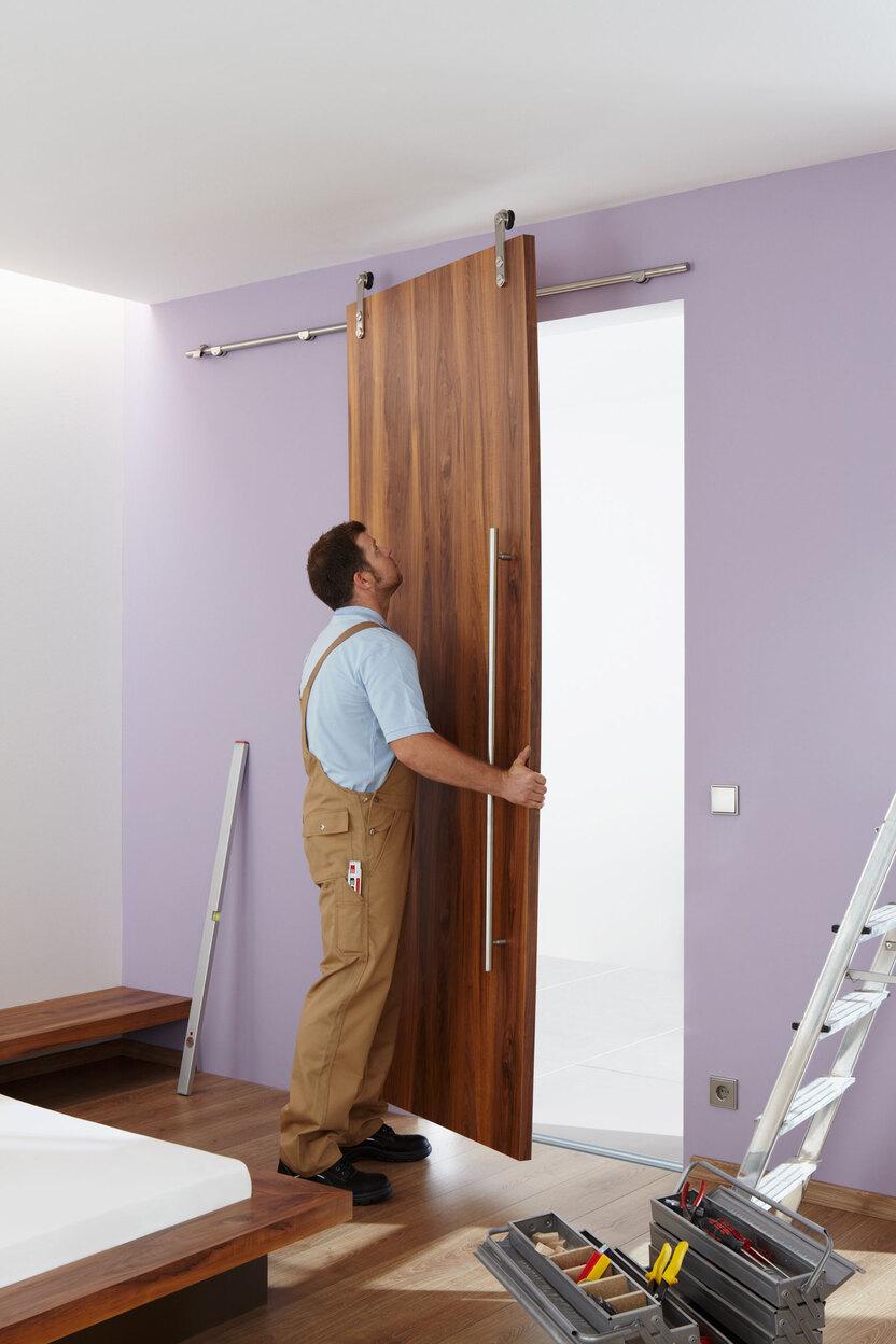 Einhängen einer losen Holzschiebetür in Edelstahlschienen durch einen Schreiner