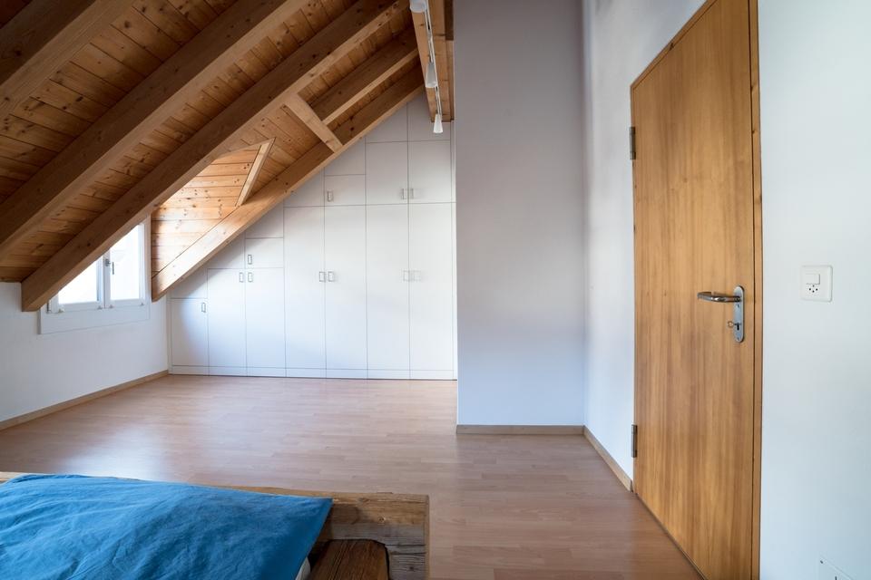 Nischenlösung für weißen Einbauschrank mit Schubladen und Türen an in dunklem Holz belassener Dachschräge