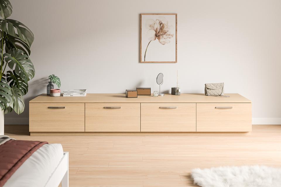 Ein maßgeschneidertes Sideboard aus hellem Holz mit dekorativen Gegenständen und einer Pflanze in einem schlichten Raum.